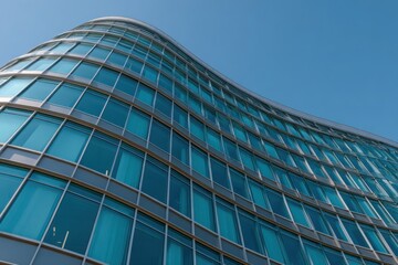 Obraz premium Modern curved glass skyscraper reflecting the clear blue sky on a bright day