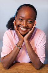 Smiling African young woman poses indoors wearing a pink shirt