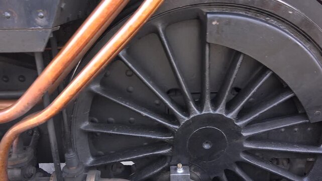 Close up of steam train wheels turning as locomotive moves away from a station as tourists take heritage transport in England UK 4K
