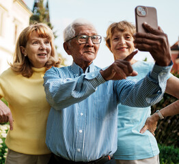Joyful older adults happily taking a fun selfie together in a beautiful autumn park setting