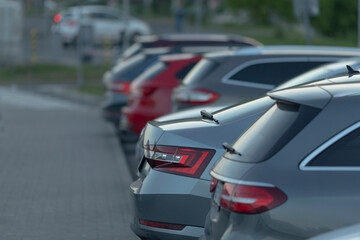 A lineup of several gray and red SUVs is parked in the midst of a bustling urban environment, showcasing city life