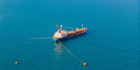 Tanker oil ship anchored in vibrant blue waters, aerial top view © Parilov