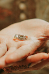 Close-up shows ornate wedding rings on a palm with henna tattoos, symbolizing commitment and love.