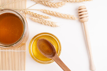 Jar of honey with wooden honey dipper on white kitchen background. Tasty honey bunker.