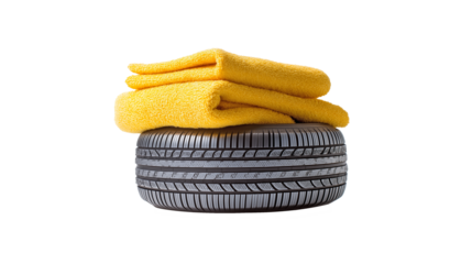A tire rests firmly on a flat surface, topped with two vibrant yellow towels.