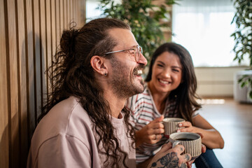 Happy couple laughing and drinking coffee at home