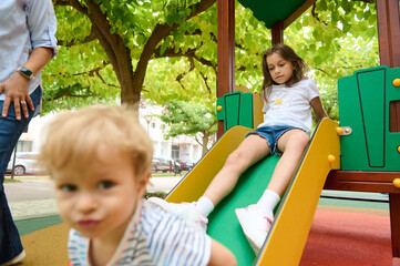Obraz premium Children Playing Happily on a Slide at a Sunny Park Playground