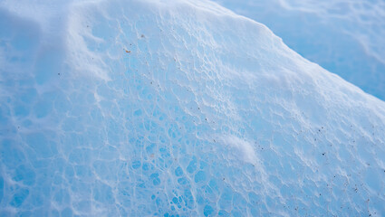 Obraz premium A closeup abstract view of the textured surface of a glacier, revealing intricate patterns of ice and water with a vibrant blue hue