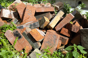 There are a lot of old bricks for building a house on a garden plot.