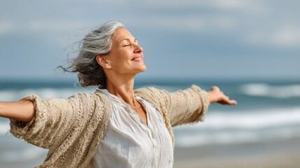 happy mature woman with arms outstretched feeling the breeze at beach beautiful middle aged woman with arms up dancing on beach mid lady feeling good and enjoying freedom at sea copy space no logos n