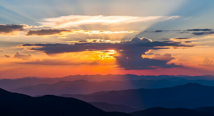 Dramatic sunset with sunbeams breaking through clouds over mountains