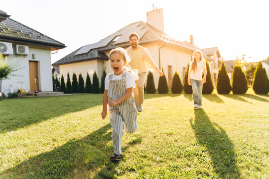 Happy family running in the garden of their modern house