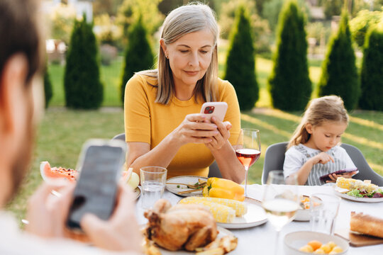 Family using smartphones during lunch in garden