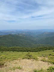 Obraz premium Wide mountain valley with forested hills and distant ridges.