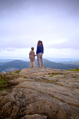 Obraz premium Two girls or sisters holding hands on the top of a mountain. Bergen, Norway,2025