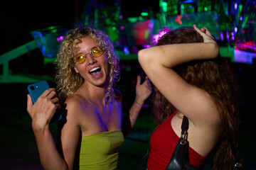 Naklejka premium Young women dancing and taking selfie at nightclub party