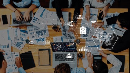 A diverse business team collaborates on data analysis, surrounded by graphs and charts on their desks, enhanced by digital icons representing modern technology concepts. Raster