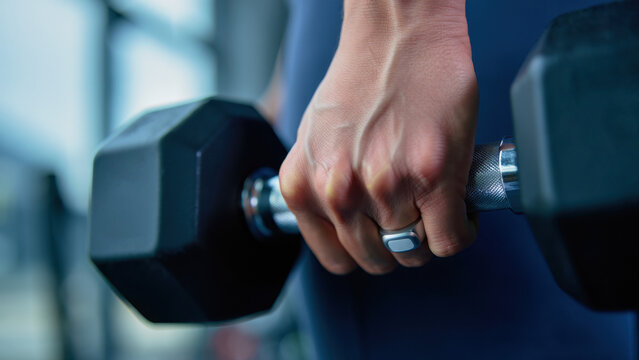 Smart ring during workout, wearable fitness tracker, close-up hand holding dumbbell, gym training moment, health monitoring device, modern fitness technology