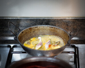 A small pot of fish curry being cooked in the kitchen.