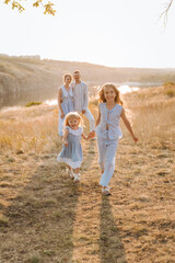  happy family having fun with two children in blue clothes on nature