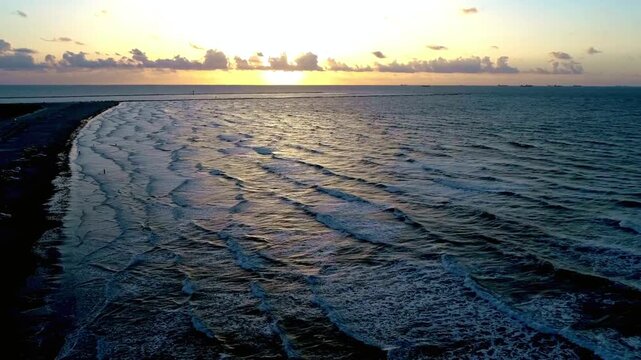 Aerial view of the ocean waves crashing on the shore at sunset in galveston, tx