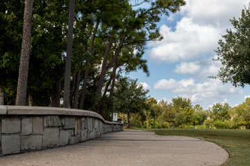 stone wall next to a walkway in a park