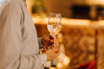 Man holding a glass of sparkling white wine in elegant restaurant interior