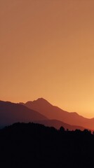 Mountain silhouettes at sunset with orange hues