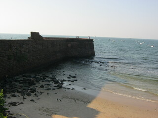 Old stone pier extending into the ocean with rocky shoreline  
