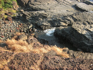 Rocky shoreline with water flowing between the stones at sunset  