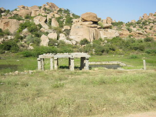 Ancient stone ruins in lush green landscape with rocky hills  