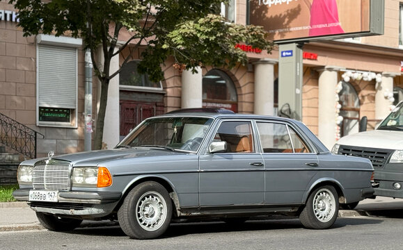 German classic car Mercedes-Benz W123 230, 1983 in the parking lot. Exterior of a the sky color sedan German manufacturer Mercedes-Benz W123 2.3 MT 230 E, 1983. 