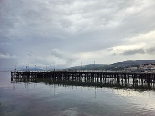Naklejka premium Long wooden pier under cloudy sky