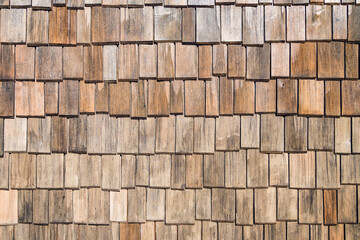 Facade cladding of wooden shingles. Small wooden boards with multicolored texture. Close-up background. Top view.