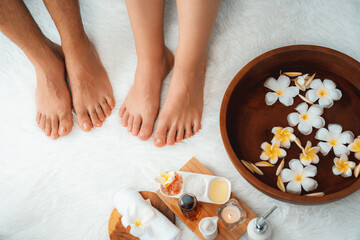Couple indulges in blissful foot massage at luxurious spa salon for reflexology therapy in gentle day light ambiance resort or hotel foot spa. Quiescent