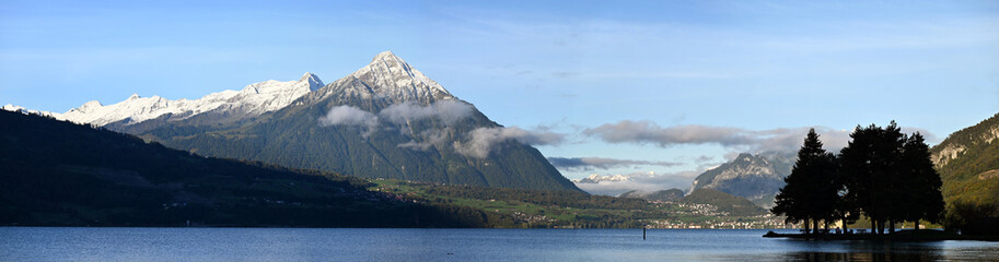 The Serene Thun Lake Surrounded by Snow-Capped Peaks Under a Clear Blue Sky
