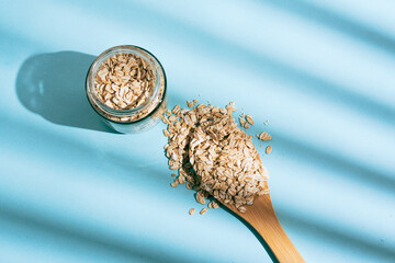 Wooden spoon in the center with scattered rice, accompanied by glass jars with cereals and natural grains. 
