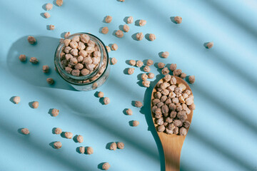 Barley grains scattered from a glass jar on a blue background. Blue background and minimalist style, soft shadows and natural light. 