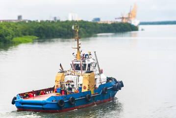Naklejka premium Tug boat sailing through the river near sea port terminal in Buenaventura, Colombia.
