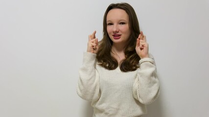 Hope, face and woman with fingers crossed in studio for feedback, results or review on blue background. Anxiety, stress or lady model with good luck emoji for wish, competition or winner announcement