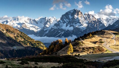 A sweeping vista of a mountain range, blanketed in snow, with a winding road snaking through the autumnal landscape.