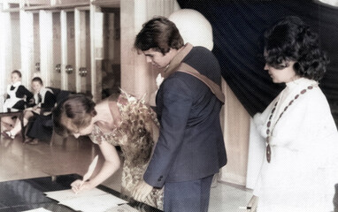Lozovaya, UkrSSR, USSR - circa 1980: The bride's witness certifies the signature in the marriage book. The groom's best man stands nearby. Retro photo