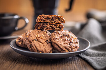 Sweet chocolate cookies on plate on wooden table.
