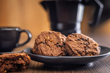Sweet chocolate cookies on plate on wooden table.