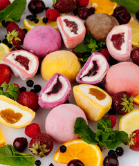 Colorful assorted mochi ice cream with fresh berries, citrus and mint on white background