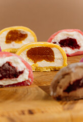 Assorted colorful mochi ice cream halves on wooden board, close-up view, studio lighting