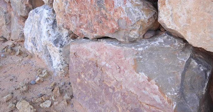 Closeup of dry stack rock wall starting at rocky sand ground with camera moving across showing all the colors and shapes of rocks 4k