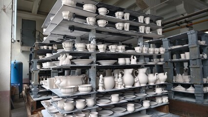 porcelain products on the shelves at the factory, prepared for firing in the kiln. Tableware Making