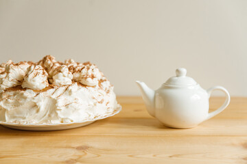 Homemade cake decorated with cream and a white teapot (in a blur).