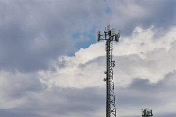 A tall communication tower with multiple antennas stands against a cloudy sky in Saskatoon.